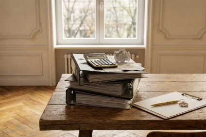 Stapel mit Aktenordnern und Schlüsseln auf einem Tisch, symbolisch für den bürokratischen Aufwand beim privaten Immobilienverkauf in Nürnberg.