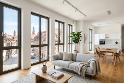 Bright Open-plan Living Area with a Gray Sofa, Wooden Coffee Table, and Large Windows Overlooking a Historic Town.