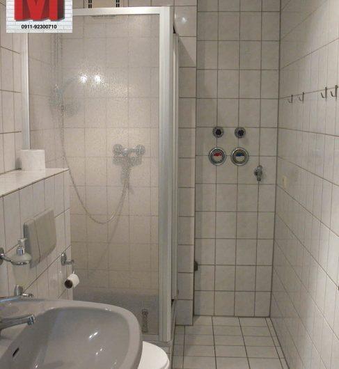 Gefliestes Badezimmer mit Duschkabine und Anschlussmöglichkeiten.