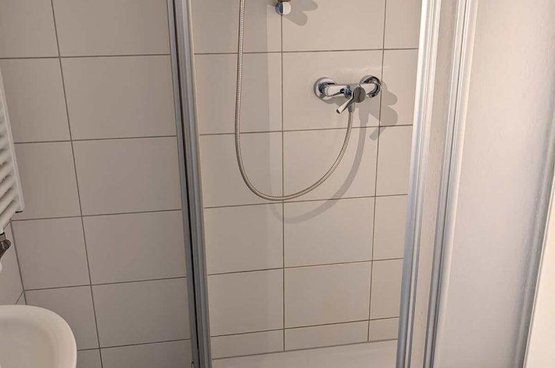 Modernes Badezimmer mit Glas-Duschkabine und hellen Fliesen.