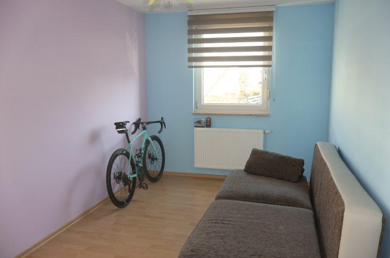 Helles Zimmer im 1. OG, aktuell als Büro genutzt, mit Laminatboden und farbigen Akzentwänden.