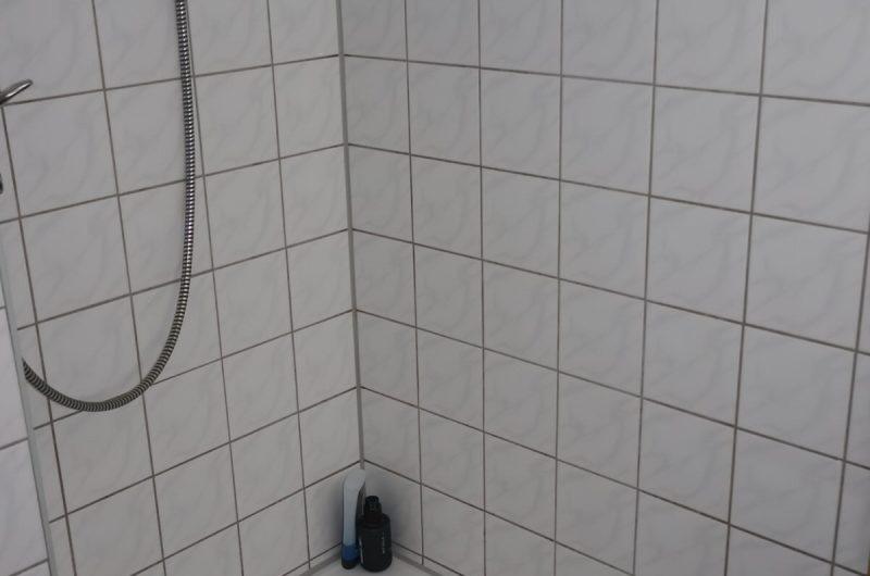Detailansicht der Dusche im hellen Badezimmer der 1-Zimmer-Wohnung.