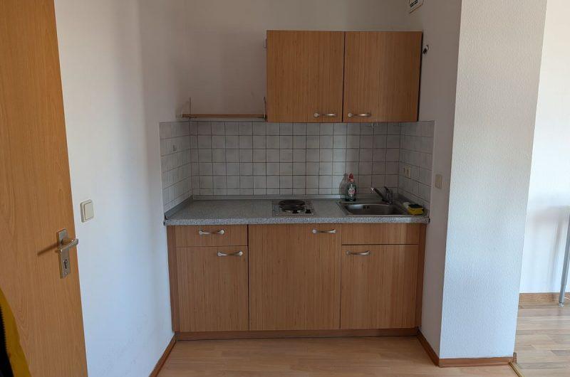 Funktionale Singleeinbauküche mit Holzfronten und Kochfeld in einer Mietwohnung in Nürnberg Gleishammer.