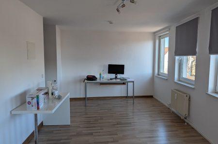 Blick in das helle Einzimmerapartment mit Stellplatzbeispiel für einen Schreibtisch und modernem Bodenbelag.