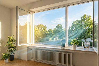 Weit geöffnetes Fenster zum Stoßlüften in einer hellen Wohnung, um Schimmelbildung und Feuchtigkeitsschäden zu vermeiden.