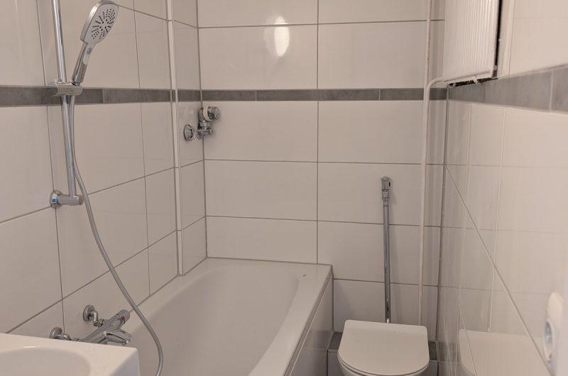 Modernisiertes Badezimmer mit neuer Badewanne und hellen Fliesen.