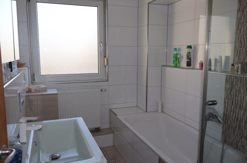 Modern gefliestes Tageslichtbad im 1. Obergeschoss mit großer Badewanne und stilvollem Waschtisch.