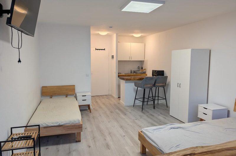 Blick in das teilmöblierte Zimmer mit Betten, TV und modernem Laminatboden in der Bayreuther Str. 19.