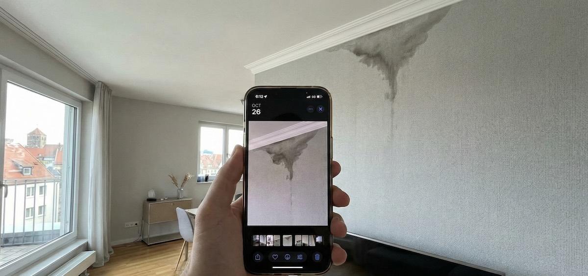 Wasserschaden an einer Tapete in einer Wohnung in Nürnberg, der mit einem Smartphone dokumentiert wird.