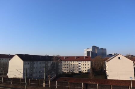 Weitläufiger Ausblick vom Balkon über die Dächer von Nürnberg bei blauem Himmel.