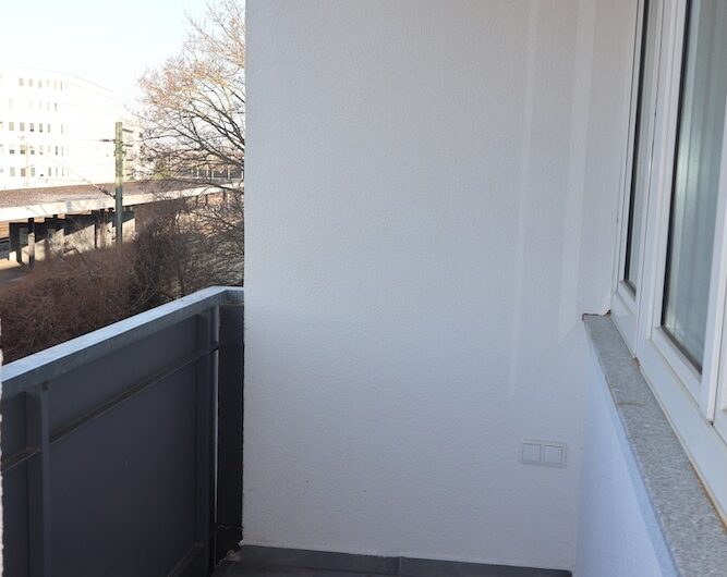 Saniert Balkon mit grauen Fliesen und praktischen Außensteckdosen für Homeoffice im Freien.