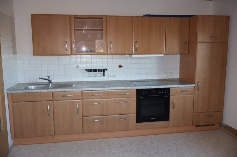 Gepflegte Einbauküche in Holzoptik mit Herd, Backofen und Spüle.