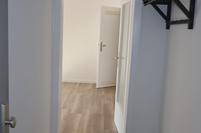 Heller Flur mit neuem Holzboden und Blick in das Wohnzimmer einer sanierten Wohnung in Nürnberg.