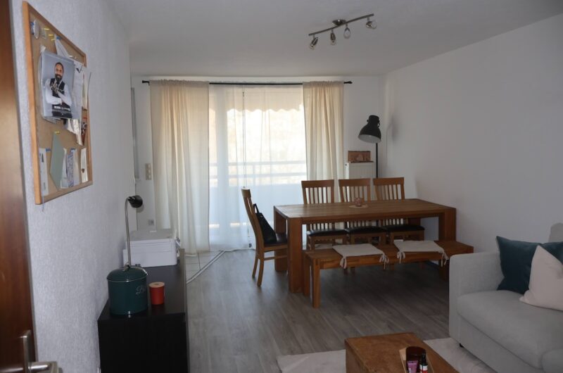 Helles Wohnzimmer mit Laminatboden und Zugang zum Balkon