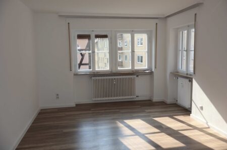 Lichtdurchflutetes Wohnzimmer mit frischem Anstrich und neuem Laminatboden in Holzoptik.