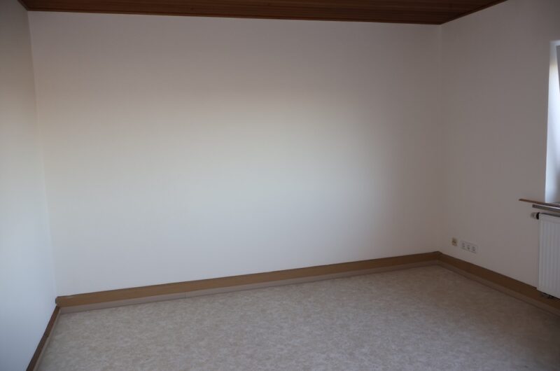 Lichtdurchflutetes Wohnzimmer mit hellem Vinylboden und weißen Wänden.