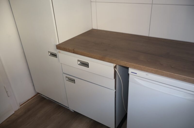 Detailansicht der sanierten Einbauküche mit Markenkühlschrank und weißen Fronten.