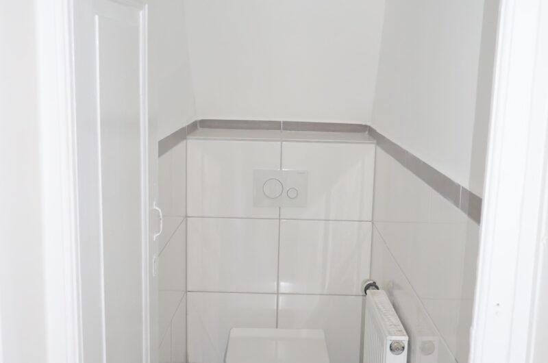 Modernes, hell gefliestes Gäste-WC unter der Schräge in der Maisonette-Wohnung.