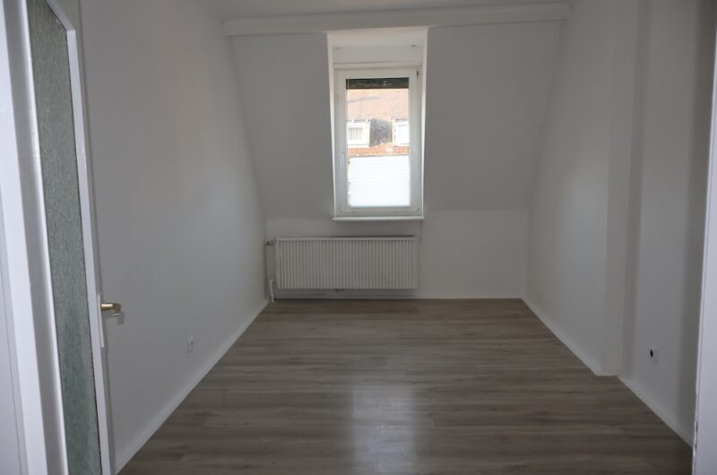 Helles, geräumiges Schlafzimmer mit modernem Laminatboden und weißer Wandgestaltung.