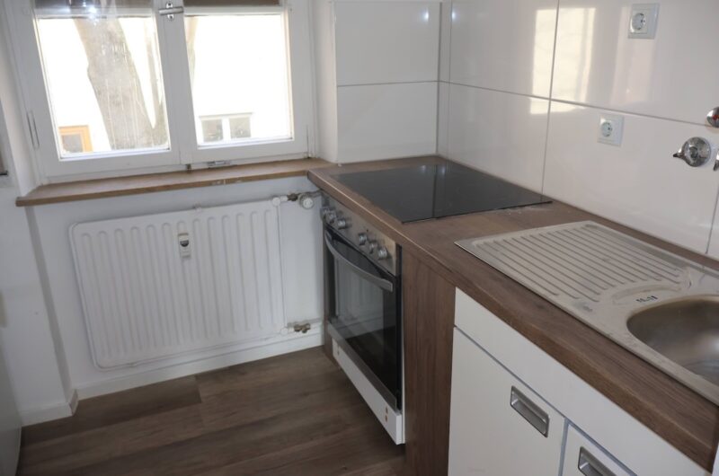 Separate Küche mit neuer Arbeitsplatte in Holzoptik, Cerankochfeld und Fenster.