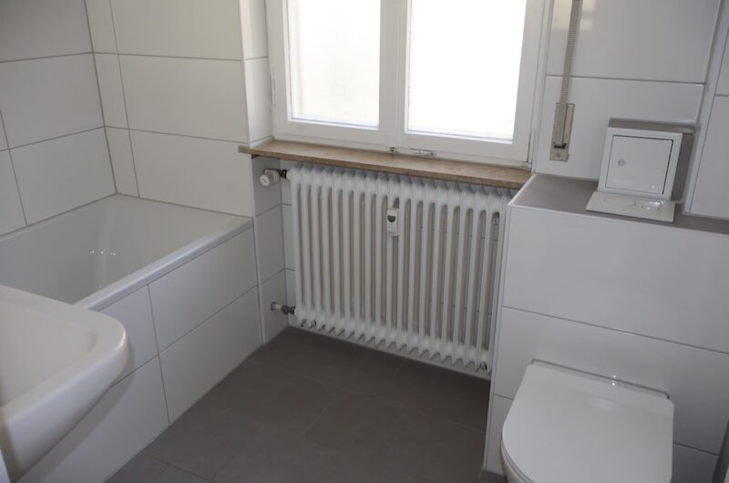 Modernes WC und neuer Heizkörper im sanierten Tageslichtbad der Immobilie in den Sieben Zeilen.