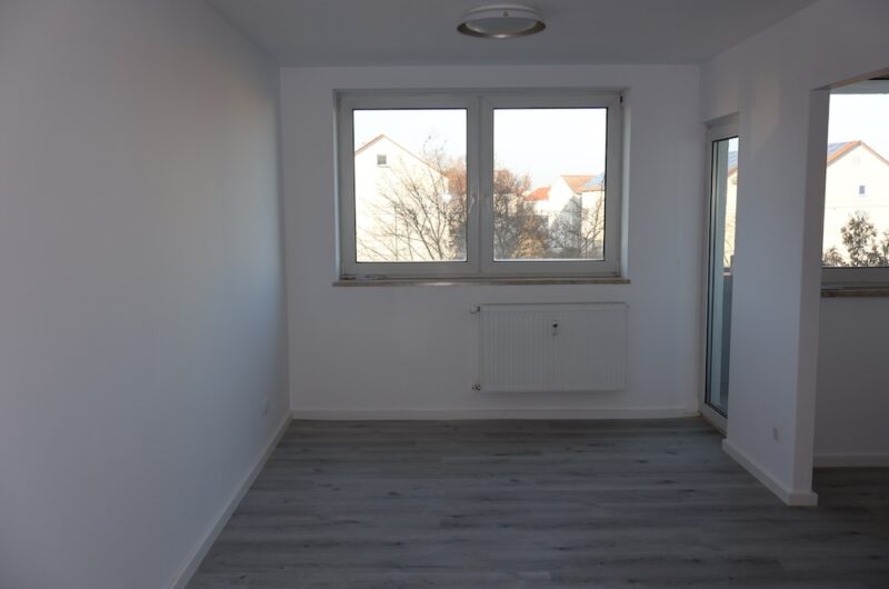 Lichtdurchflutetes Wohnzimmer mit hochwertigem Vinylboden und Balkonzugang.