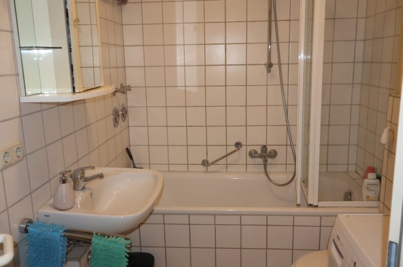 Hell gefliestes Badezimmer mit Badewanne und Waschmaschine in Nürnberger Mietwohnung.