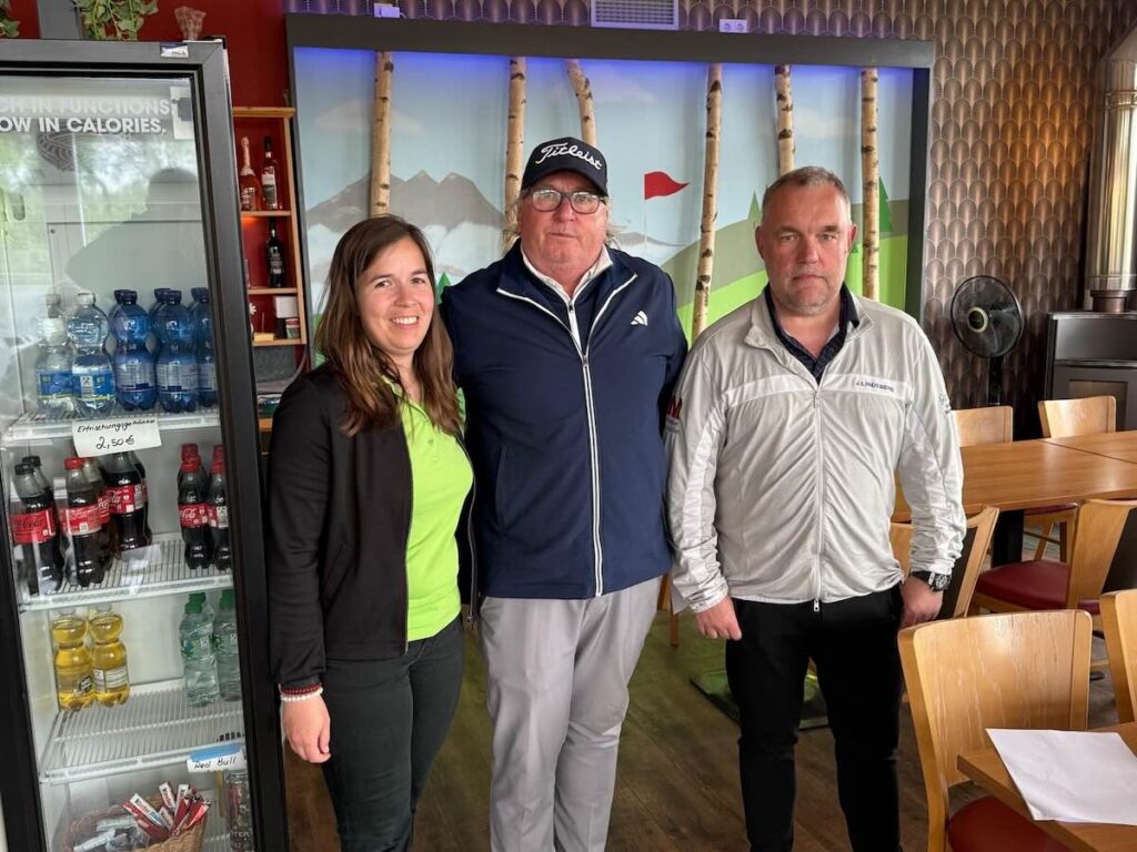Maderer-immobilien-montagsturnier-nuernberg-netto-a-thomas-faerber | Maderer Immobilien Three Adults Posing in a Casual Cafe: Woman on the Left in a Lime Shirt, Man in the Middle with a Titleist Cap, and Another Man on the Right in a Light Jacket.