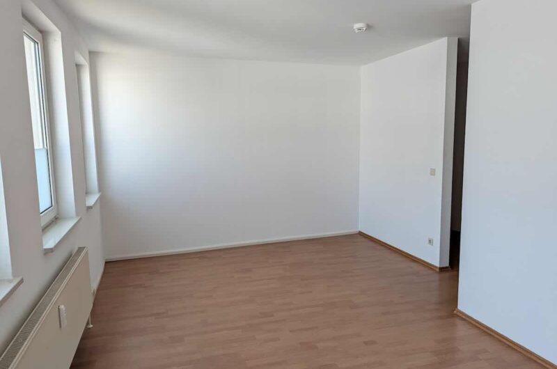 Lichtdurchfluteter Wohn- und Schlafraum mit großen Fenstern und Blick in den ruhigen Innenhof.