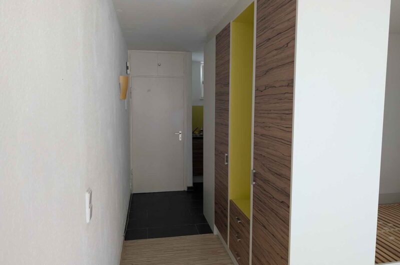 Gepflegter Flur der Mietwohnung in der Oberen Schmiedgasse mit dunklen Fliesen, hellem Laminat und Blick auf den integrierten Garderobenschrank.