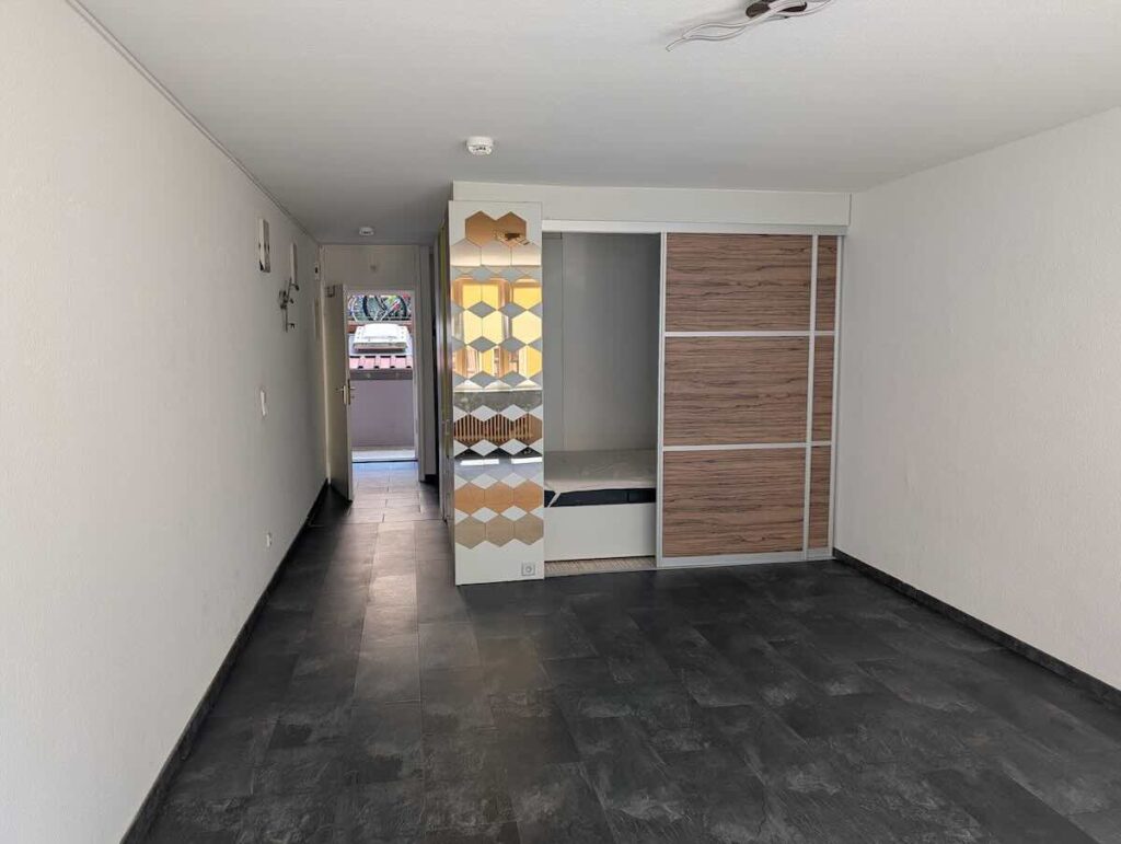 Schrankbett-kombination-singlewohnung-nuernberg-zentrum | Maderer Immobilien Cleveres Raumkonzept: Maßgefertigte Schrankwand Mit Integriertem Schlafbereich, Schiebetüren Und Spiegel-details in Einem Sanierten Apartment in Nürnberg.