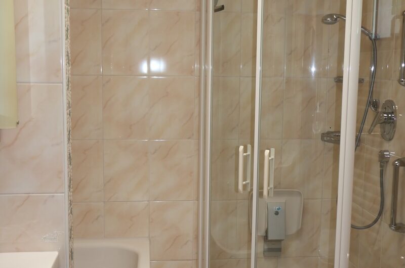 Modernisiertes Tageslichtbad mit Badewanne und Duschkabine, hell gefliest.