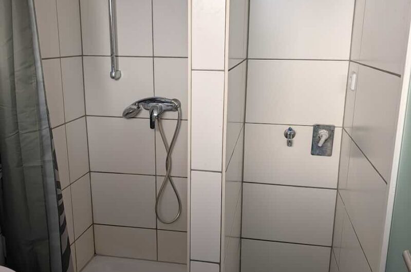 Saniertes Badezimmer mit weißen Fliesen, hängendem WC und Waschbecken im 1. Obergeschoss der Nürnberger City-Wohnung.