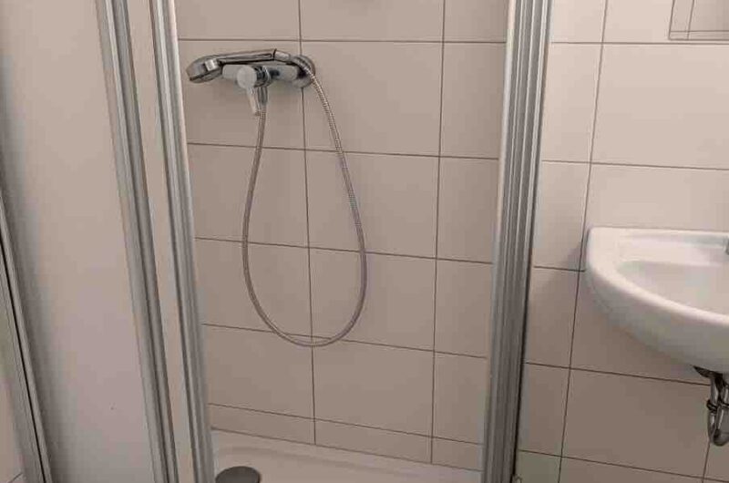 Modernes Badezimmer mit Duschkabine und deckenhohen Fliesen in einer 1-Zimmerwohnung in Nürnberg Zentrum.