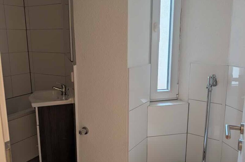 Modernes Badezimmer mit großem Fenster und dunklen Bodenfliesen