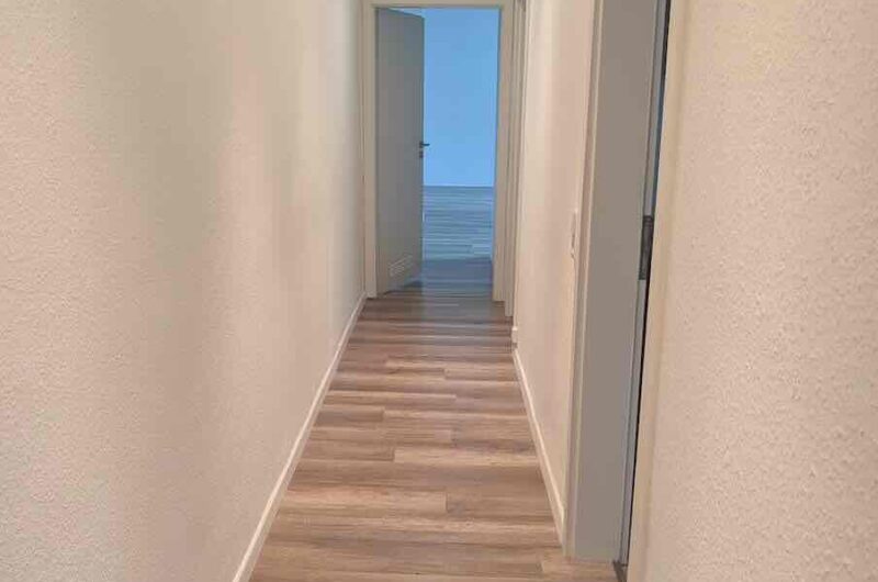 Einladender Flur mit durchgehendem Laminatboden und modernen Deckenspots