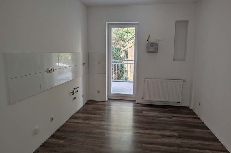 Separate Küche mit hellem Fliesenspiegel, Platz für einen Essbereich und direktem Zugang zum Balkon in der Nürnberger Gugelstraße.
