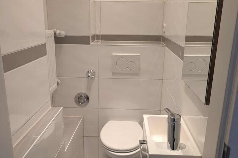 Modernes separates WC mit hellen Fliesen in einer denkmalgeschützten Nürnberger Altstadtwohnung.