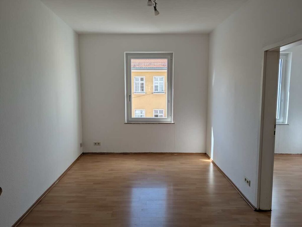 Wohnzimmer-2-zimmer-wohnung-nuernberg | Maderer Immobilien Geräumiges Wohnzimmer Mit Großem Fenster Und Laminat in 2-zimmer-wohnung.