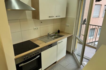 Moderne, voll ausgestattete Einbauküche mit direktem Zugang zum Balkon in Nürnberg – Maderer Immobilien