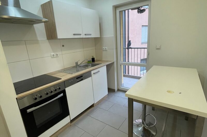 Moderne, voll ausgestattete Einbauküche mit Hochtisch und direktem Zugang zum Balkon in Nürnberg – Maderer Immobilien