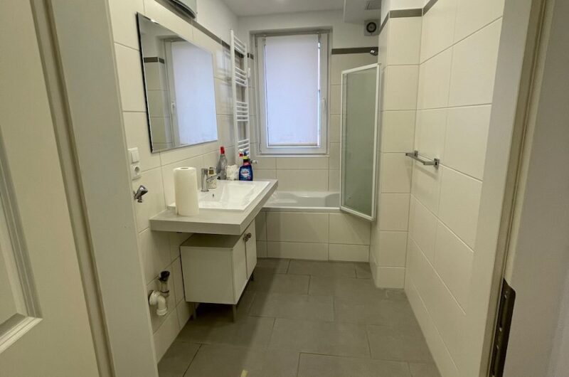 Hell gefliestes Tageslichtbad mit Badewanne und Duschwand in der Nürnberger City – Maderer Immobilien