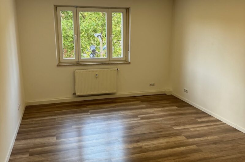 Großzügiges Wohnzimmer mit Blick auf alten Baumbestand und feinem Holzparkett – Maderer Immobilien